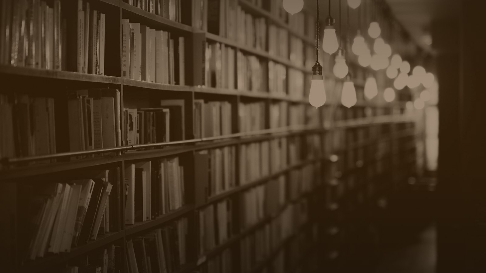 Sepia-toned photo of library shelves under hanging bulbs
