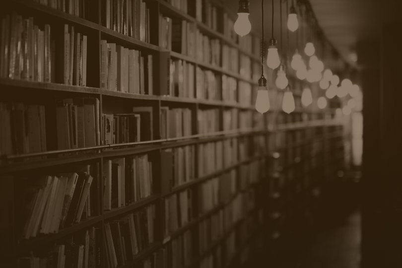 Sepia photo of long library shelves, representing the directories and databases AI quotes about you