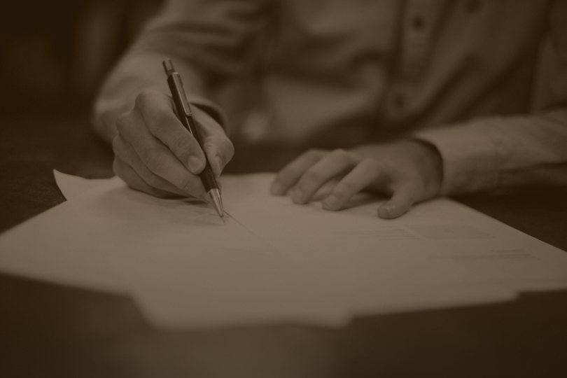 Sepia photo of a person working through documents with a pen, representing every AI answer read by hand