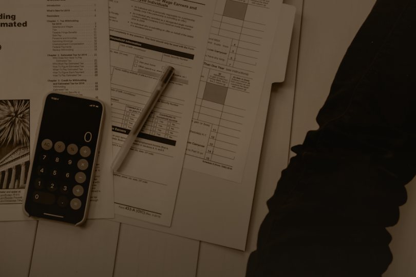 Sepia photo of forms, a pen and a calculator, representing the written fix plan you receive