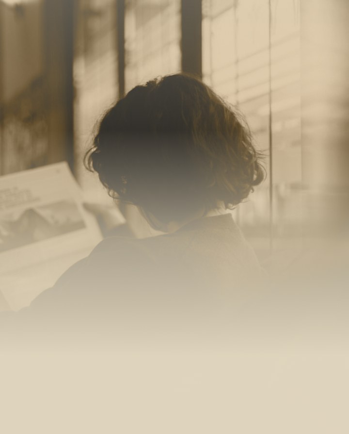 Sepia photo of a person reading by a window, representing audits read by a human expert